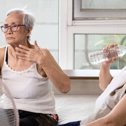 Asian elderly people who are hot and thirsty from high temperature heat waves,drinking water help to reduce body heat,prevent heat stroke,cooling herself in summer hot weather,health care concept