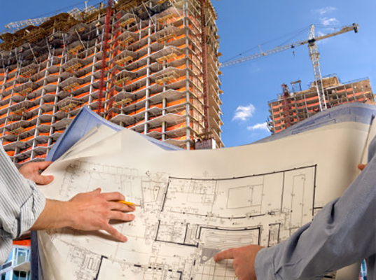 Engineers with building plans at high-rise construction site, close-up