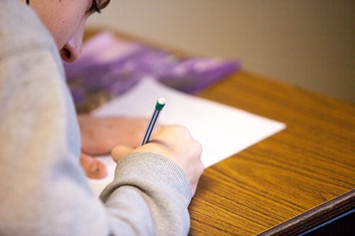 Student writing on a piece of paper during a test