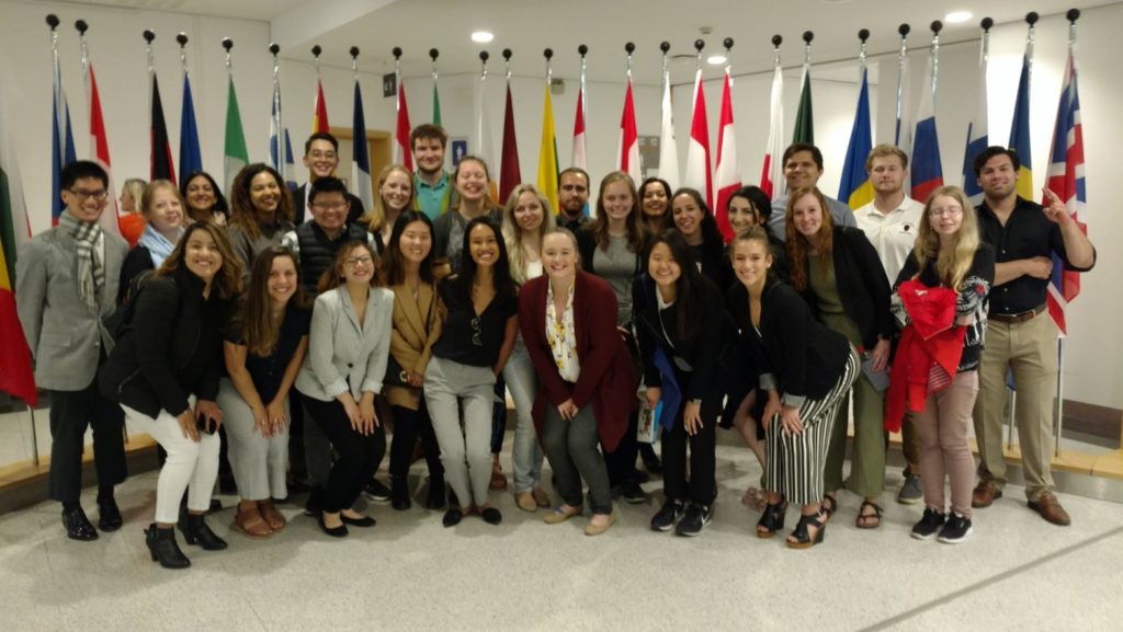 USC Price students in Germany posing for a group photo in front of international flags