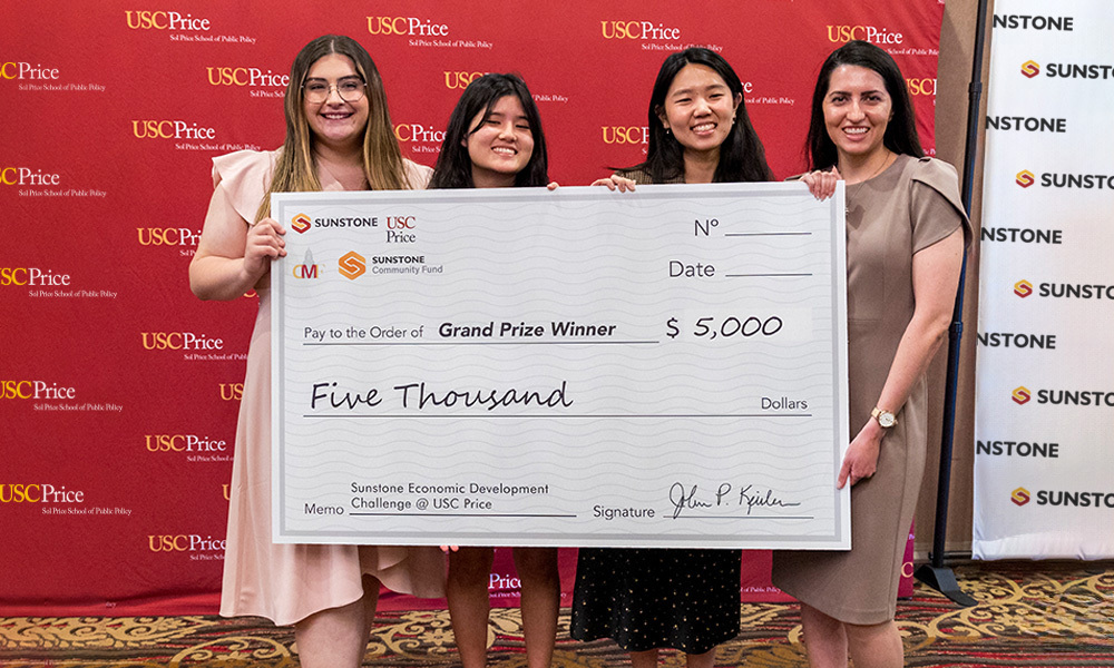 Four students hold giant check