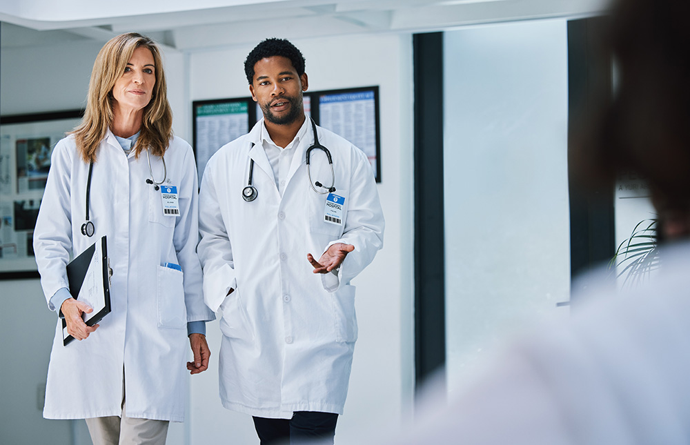 istock photo showing two doctors, one female and one male, walking down a corridor and talking together.