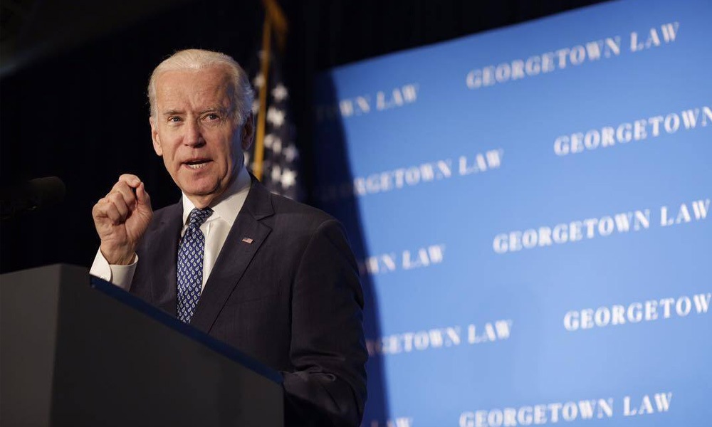 Joe Biden speaks with an American flag behind him