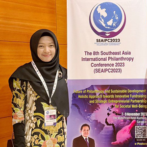 Hafiza Nofitariani poses next to a sign from the Southeast Asia International Philanthropy Conference in Malaysia.