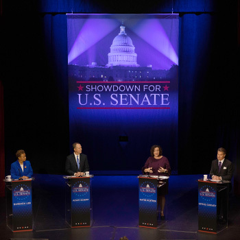 Four Senate candidates stand at podiums on stage