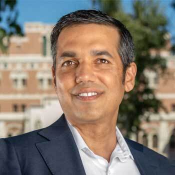 Headshot of Neeraj Sood. USC campus buildings in background
