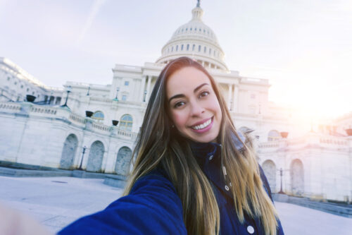 Young woman taking a selfie with the U.S. Capitol