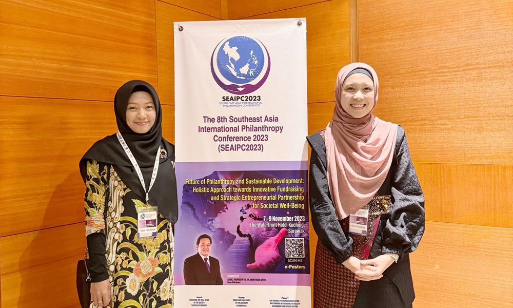 Hafiza Nofitariani (left) and her colleague pose for a picture with a sign for Southeast Asia International Philanthropy Conference in Malaysia.