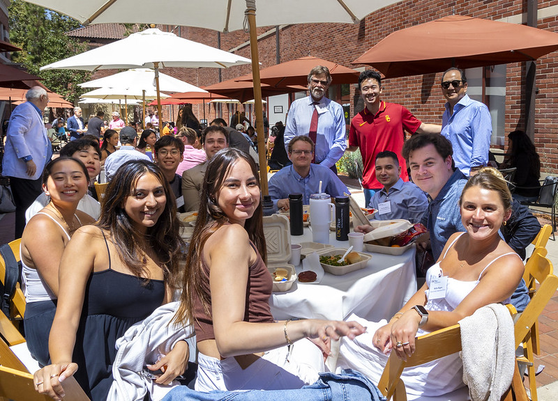 group of Masters students sitting at table in the courtyard between RGL and VPD during orientation day.