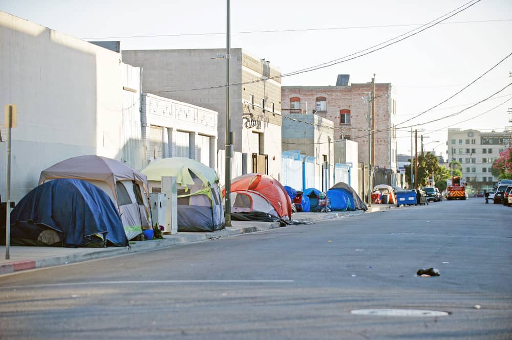 A homeless encampment of tents along the sidewalk of a street. (Courtesy: Shutterstock)