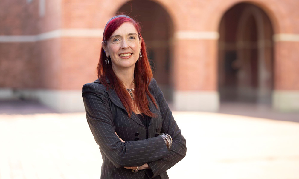 Wandi Bruine de Bruine stands with her arms crossed in front of a brick building on USC campus