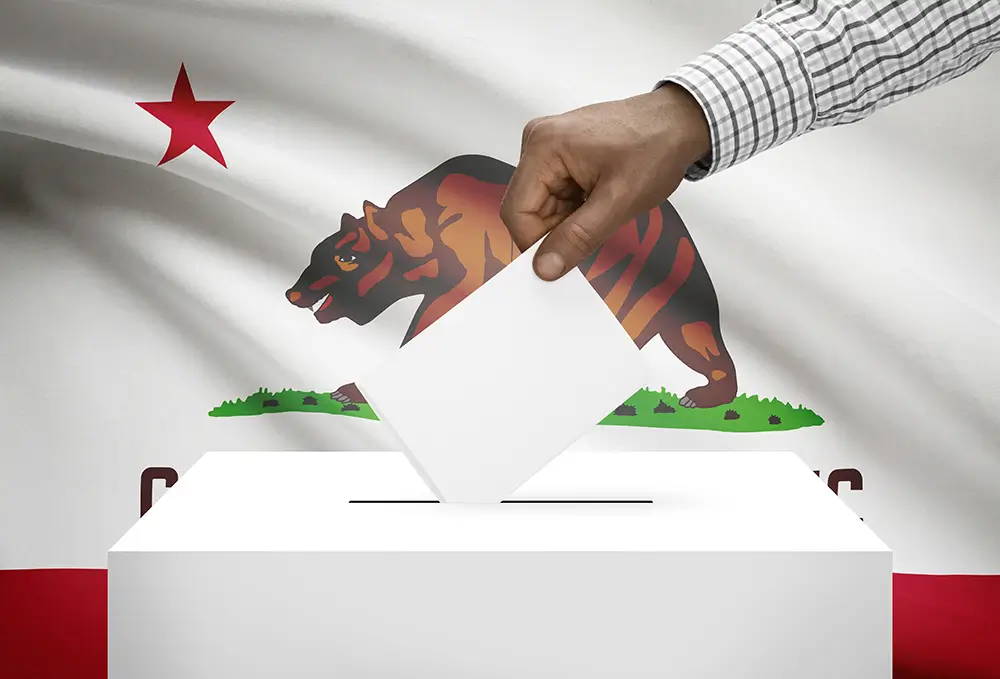 An illustration of someone putting a ballot in a ballot box with the California state flag in the background