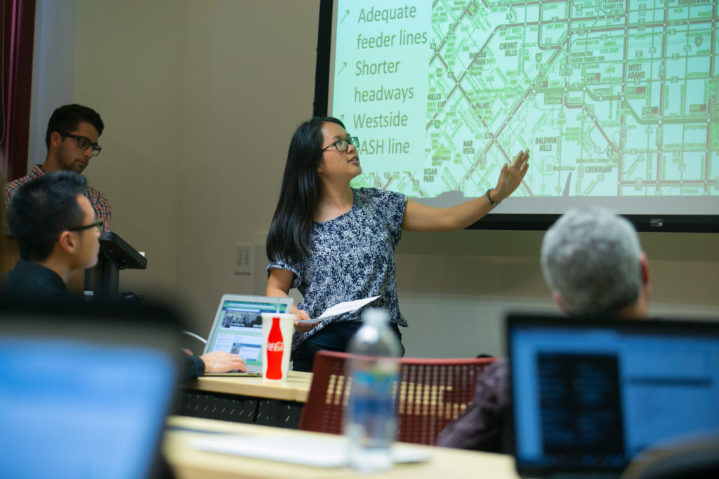 A student presenting a map in front of a classroom.