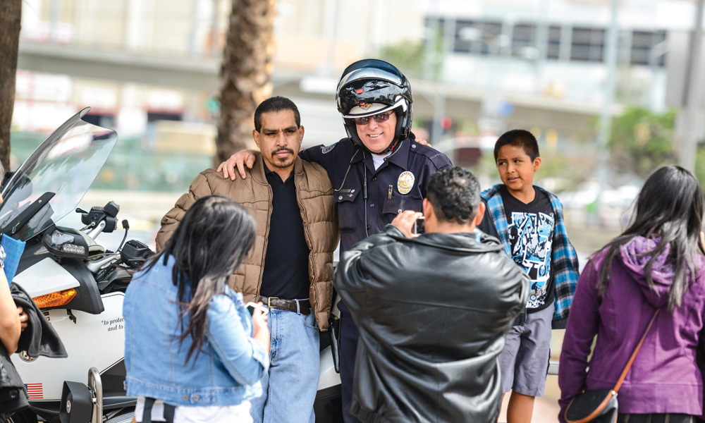 A police officer puts his arm around a man to pose for a picture