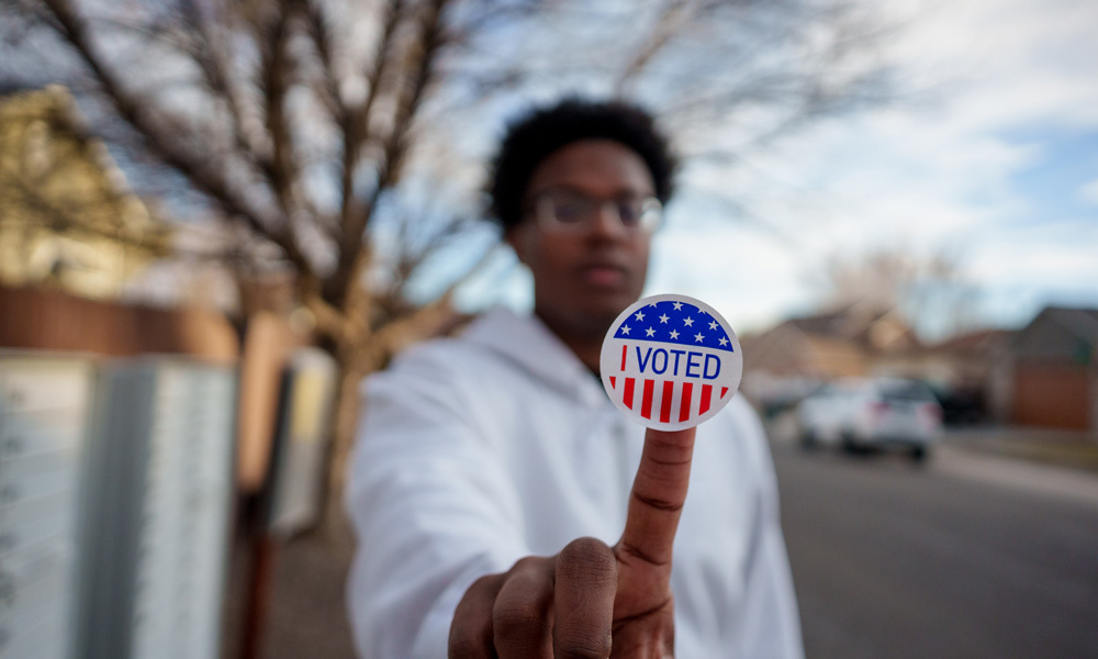 Man holds “I voted” sticker in front of camera 