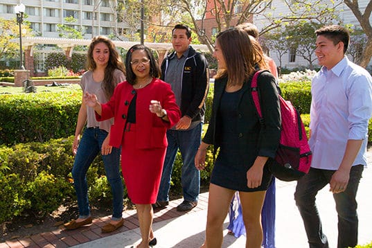 Professor Lovanna Lewis walking with students on campus.