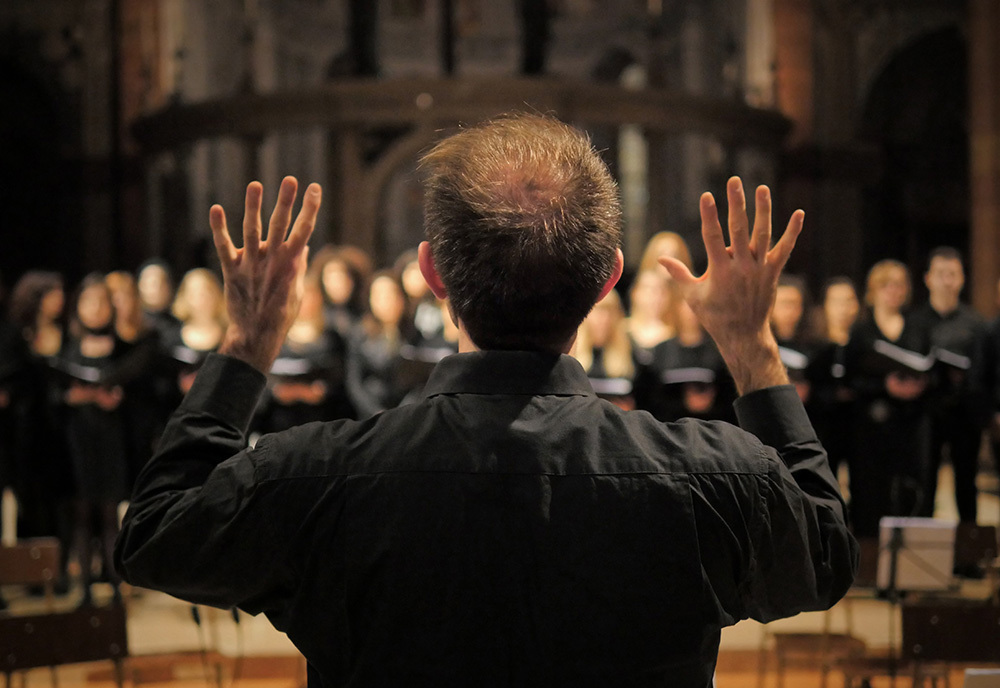 A conductor performs with a choir