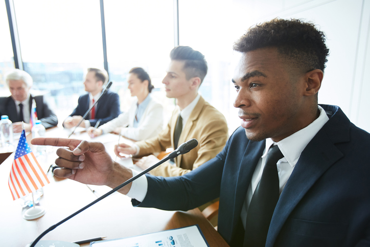 Man in suit expressing his opinion and gesturing while making statement at international meeting