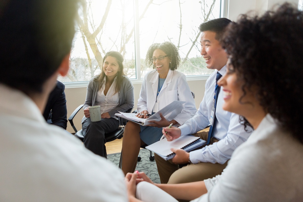 Health care professionals in white coats and students having a conversation