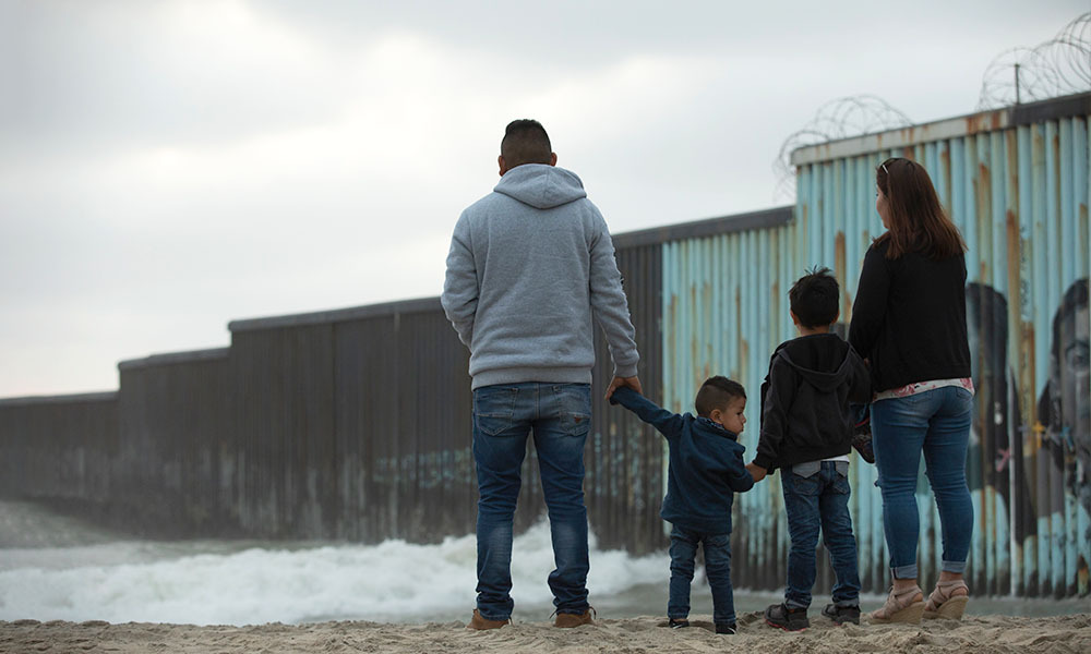 A family looks at the wall on the U.S. Mexico border