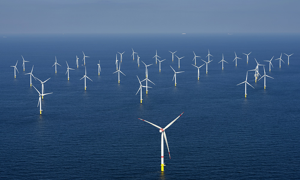 An aerial view of offshore wind turbines in the ocean.