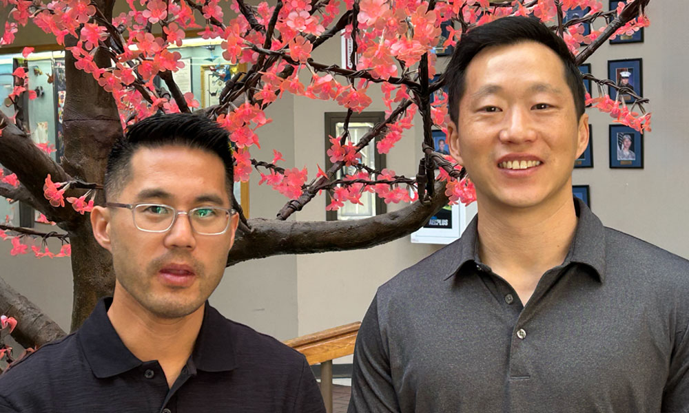 From left, Thomas Wong and Paul Lee pose for a picture in front of a cherry blossom tree